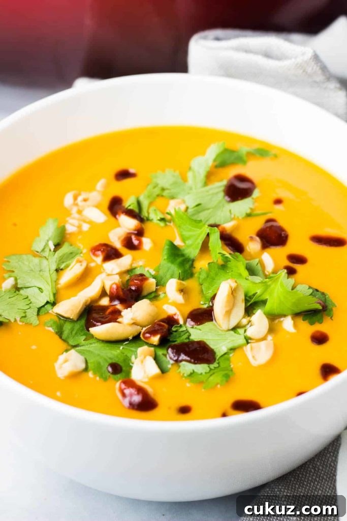 Creamy Vegan Sweet Potato Soup Recipe for Cozy Weeknights 7 A bowl of sweet potato soup topped with cilantro, chopped peanuts and sriracha
