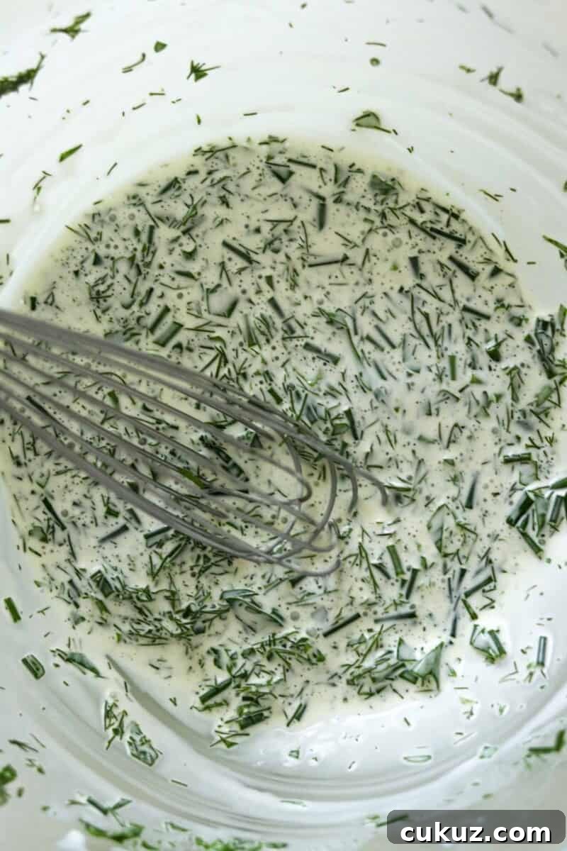 Creamy herb dressing in a bowl with a whisk.