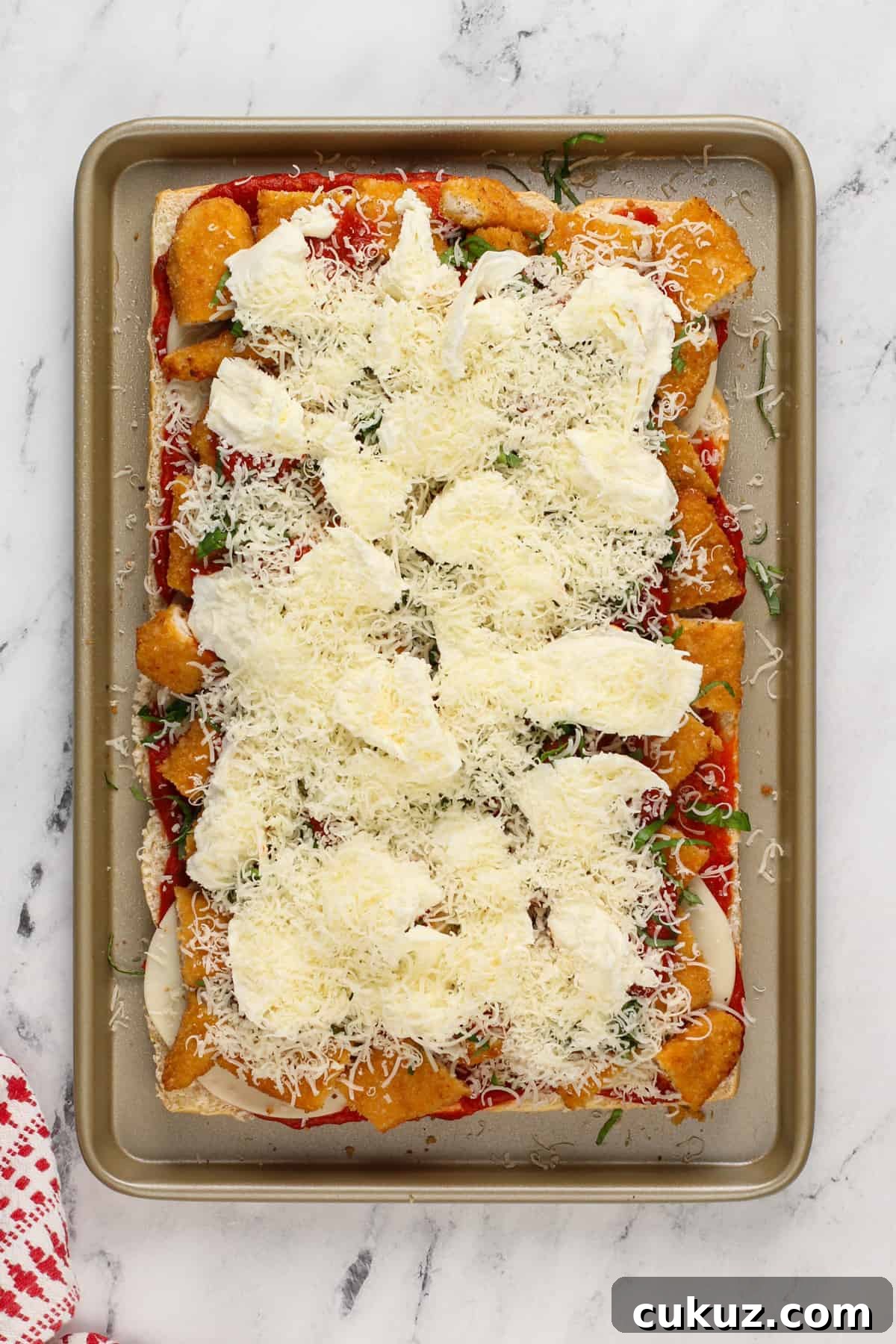 Fresh mozzarella and shredded parmesan layered onto chicken parmesan sliders.