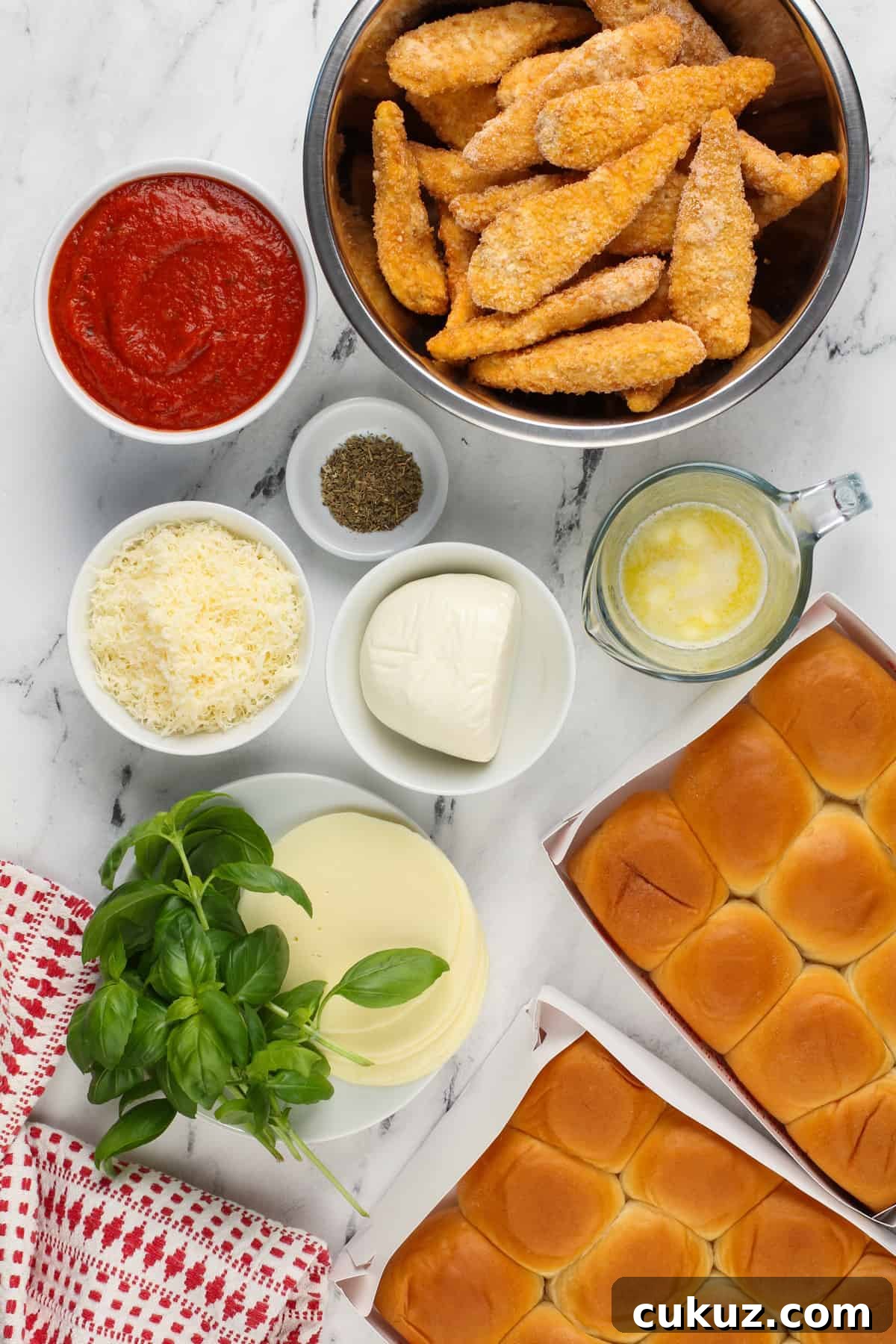 Chicken parmesan slider ingredients arranged on a white countertop.