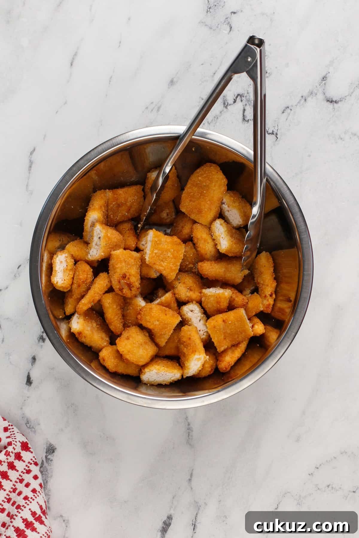 Cut up chicken tenders tossed with italian seasoning in a bowl.