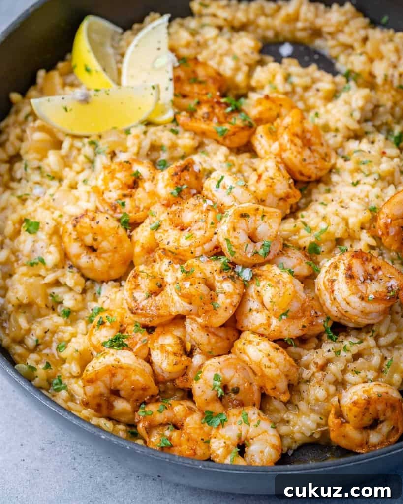side shot of risotto topped with sauteed shrimp and lemon garnishes