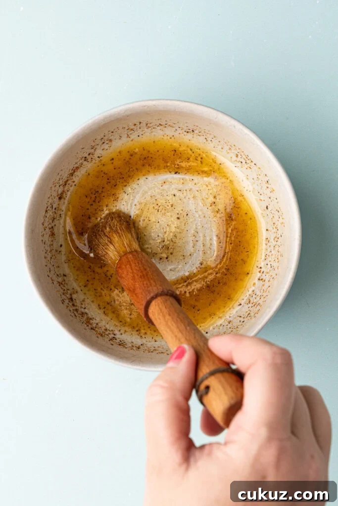 Mixing together melted butter and Cajun seasoning to make a quick Cajun butter to rub on corn on the cob. 