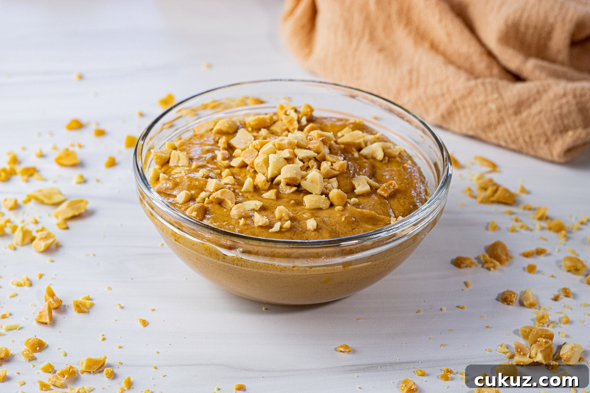 Creamy Peanut Dipping Sauce Recipe for Asian-Inspired Dishes 5 small glass bowl filled with peanut butter sauce topped with crushed peanuts