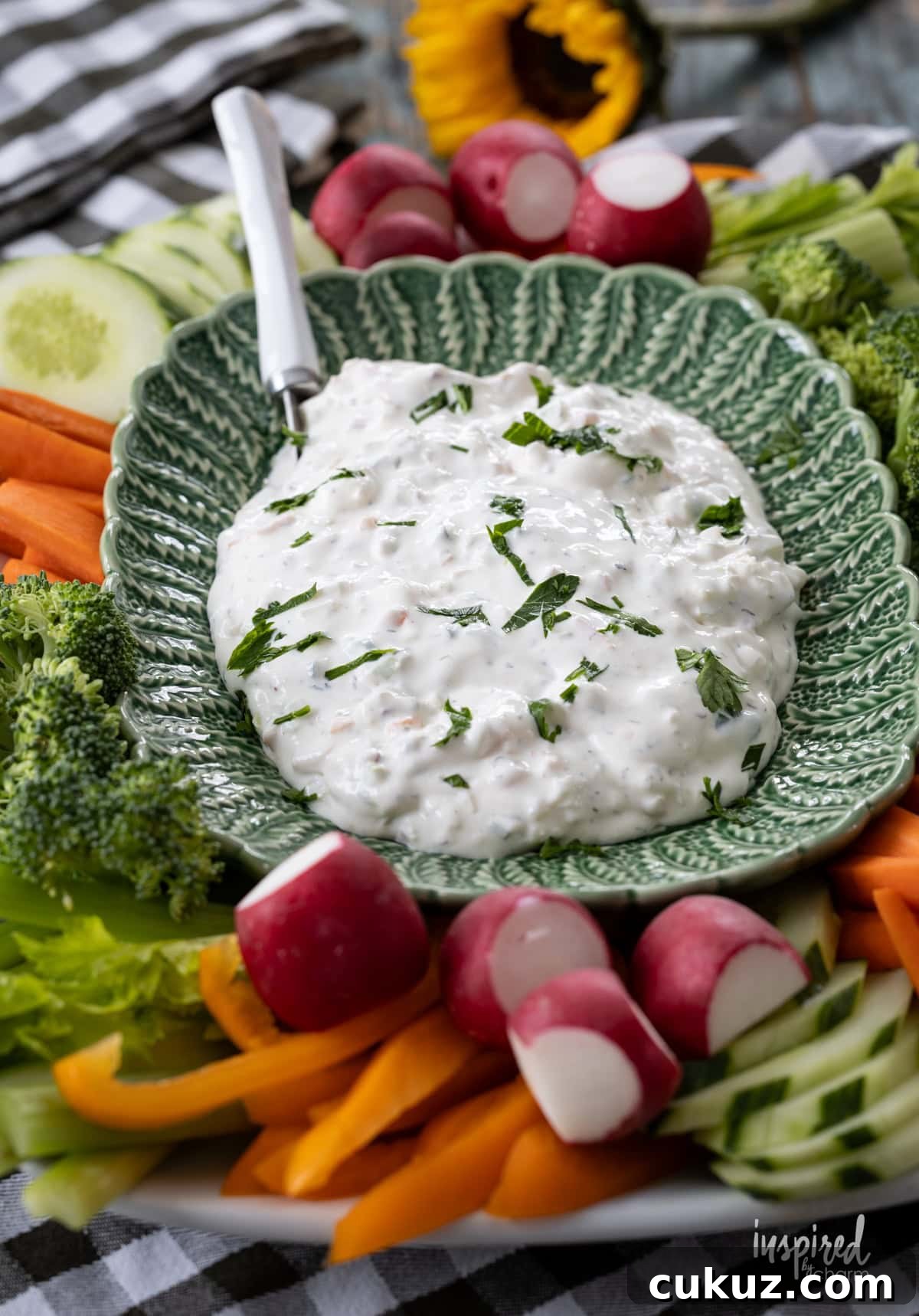 large green bowl filled with creamy garden vegetable dip and lots of vegetables around it.