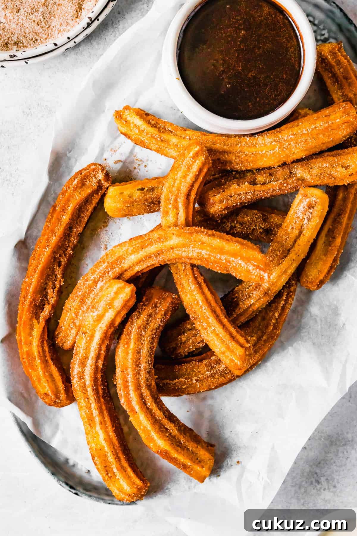 How to Make Crispy Homemade Churros with Chocolate Dipping Sauce 2 Churros recipe by easy weeknight recipes. The churros are served on a plate with a bowl of chocolate sauce.