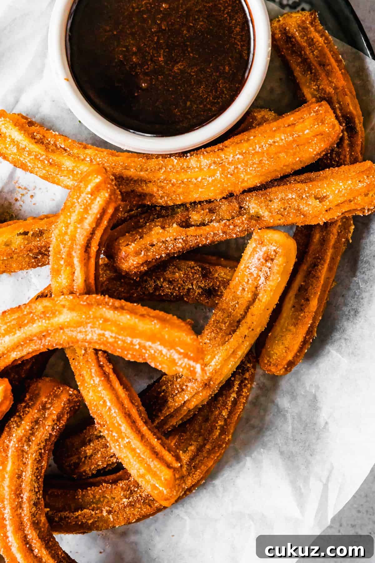 How to Make Crispy Homemade Churros with Chocolate Dipping Sauce 10 Churros recipe by easy weeknight recipes. The churros are served on a plate with a bowl of chocolate sauce.