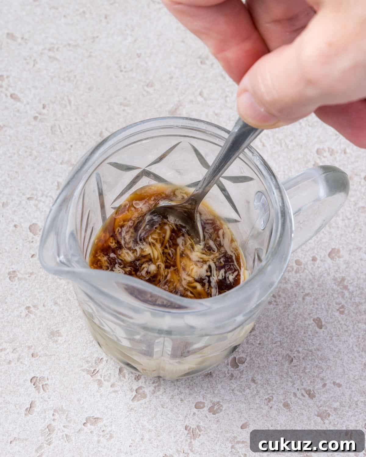 Photo showing the tahini tamari sauce ingredients being stirred together in a jug.