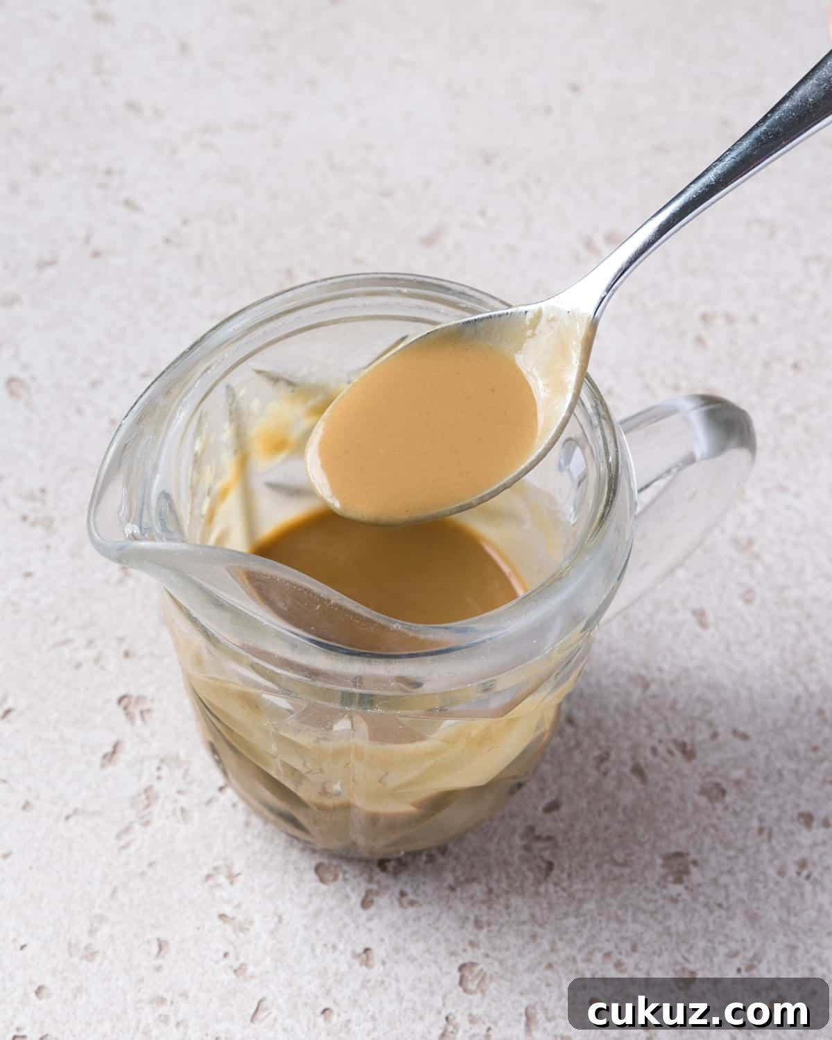 Photo showing a spoon lifting out smooth tahini sauce.