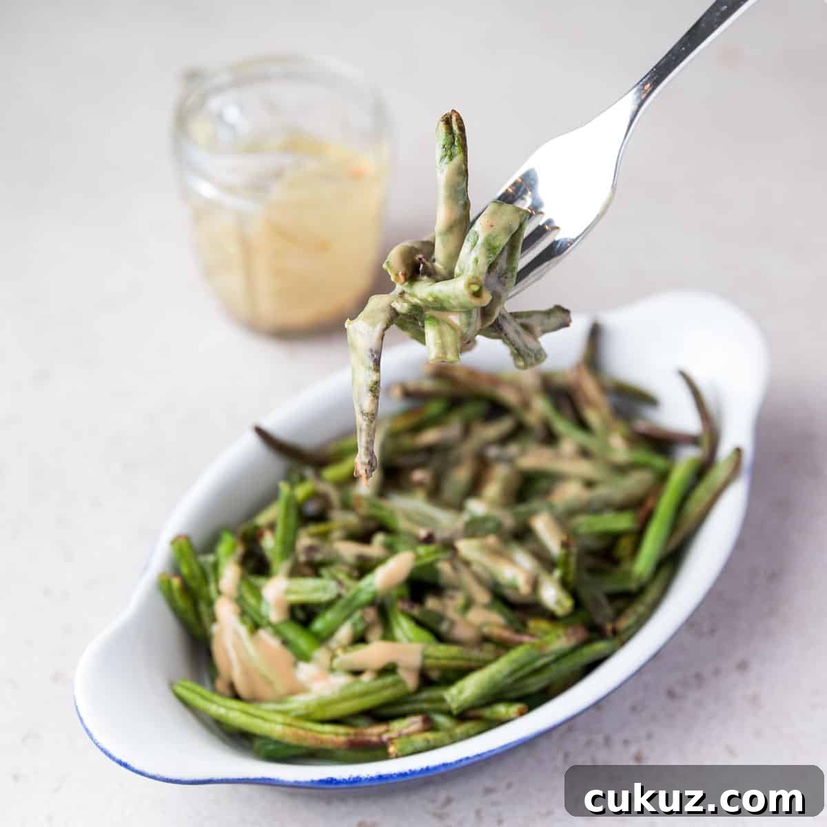 Photo showing someone taking a forkful of air fried frozen green beans.