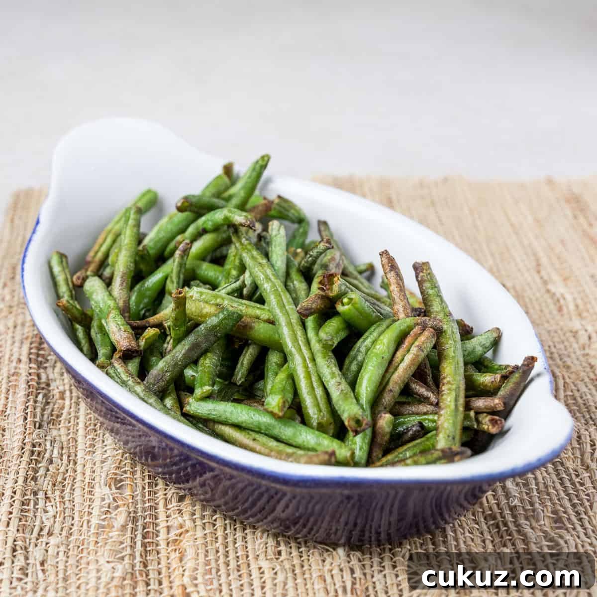 Photo showing a dish of air fried green beans on a bamboo mat.