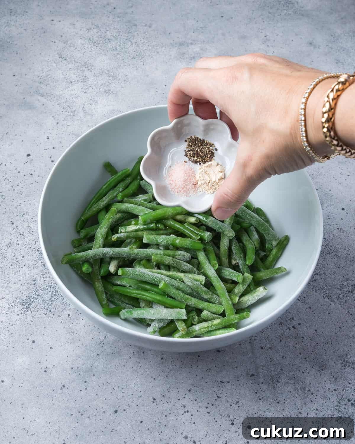 Photo showing seasoning being added to the bowl of frozen green beans.