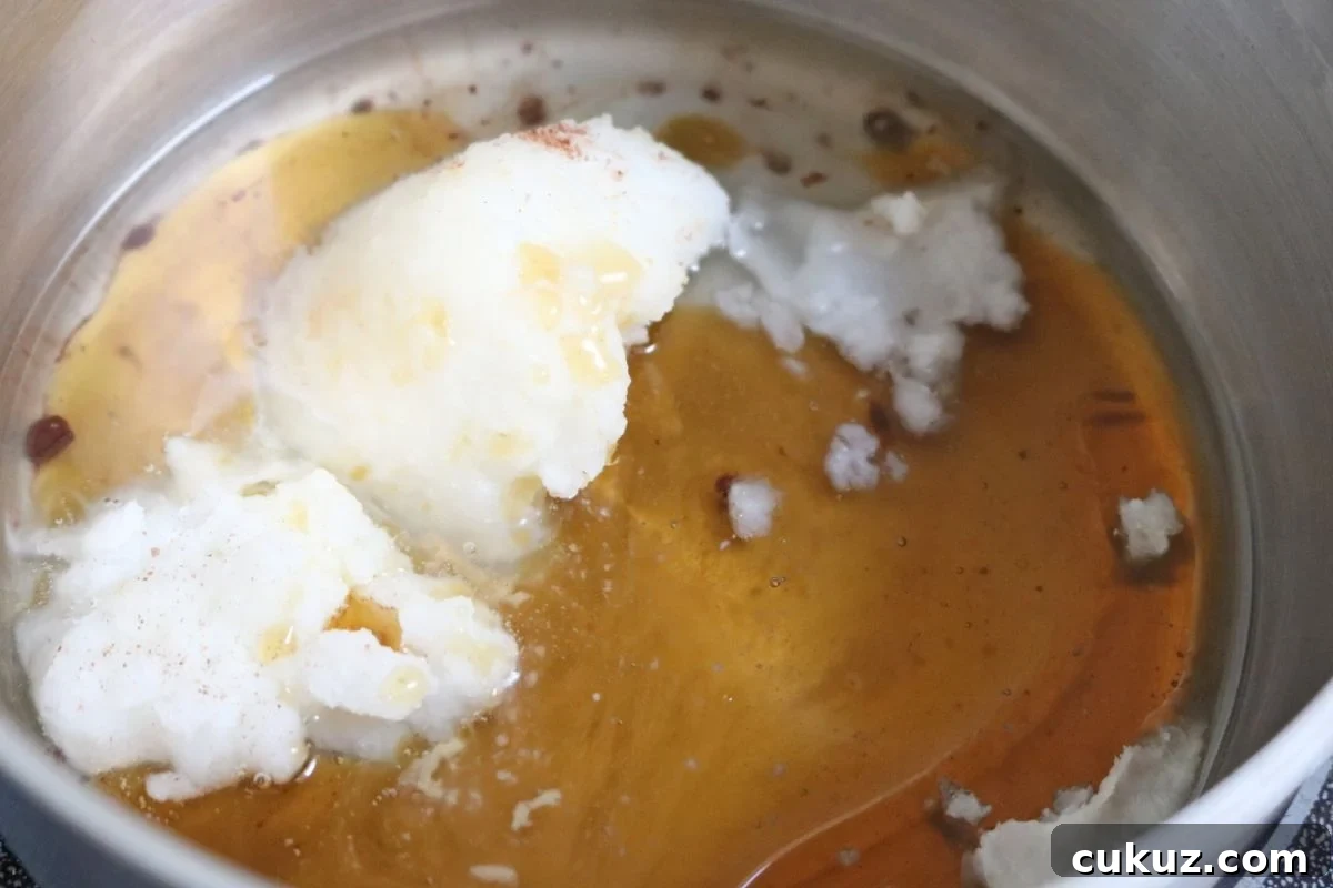 Coconut oil and maple syrup being melted in a small pot.