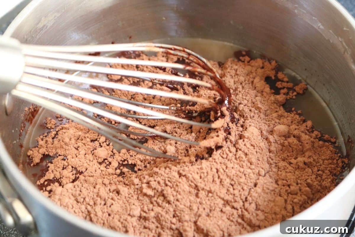 Cacao powder being mixed into a small pot with a whisk.