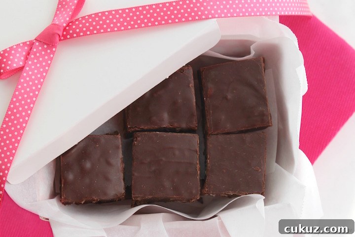 Squares of chocolate fudge layered in a white gift box with a pink bow.