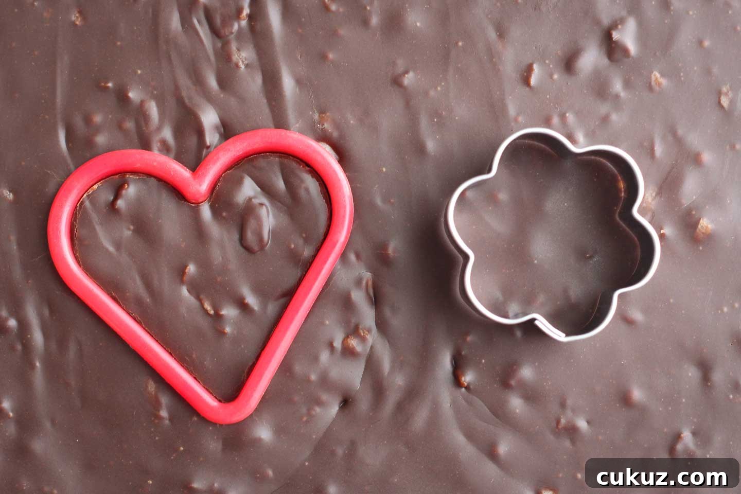 Cookie cutters cutting heart and flower shapes from finished fudge.