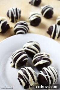 No-Bake Chocolate-Dipped Oreo Truffles 3 Portrait of Oreo Truffles covered in melted chocolate and drizzled with melted white chocolate for the professional and indulgent finish.
