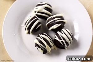 No-Bake Chocolate-Dipped Oreo Truffles 4 Above view of the five Oreo Truffles on a plate covered in melted chocolate and drizzled with melted white chocolate for the professional and indulgent finish.