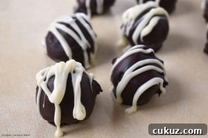 No-Bake Chocolate-Dipped Oreo Truffles 5 Close up of the Oreo Truffles covered in melted chocolate and drizzled with melted white chocolate for the professional and indulgent finish.