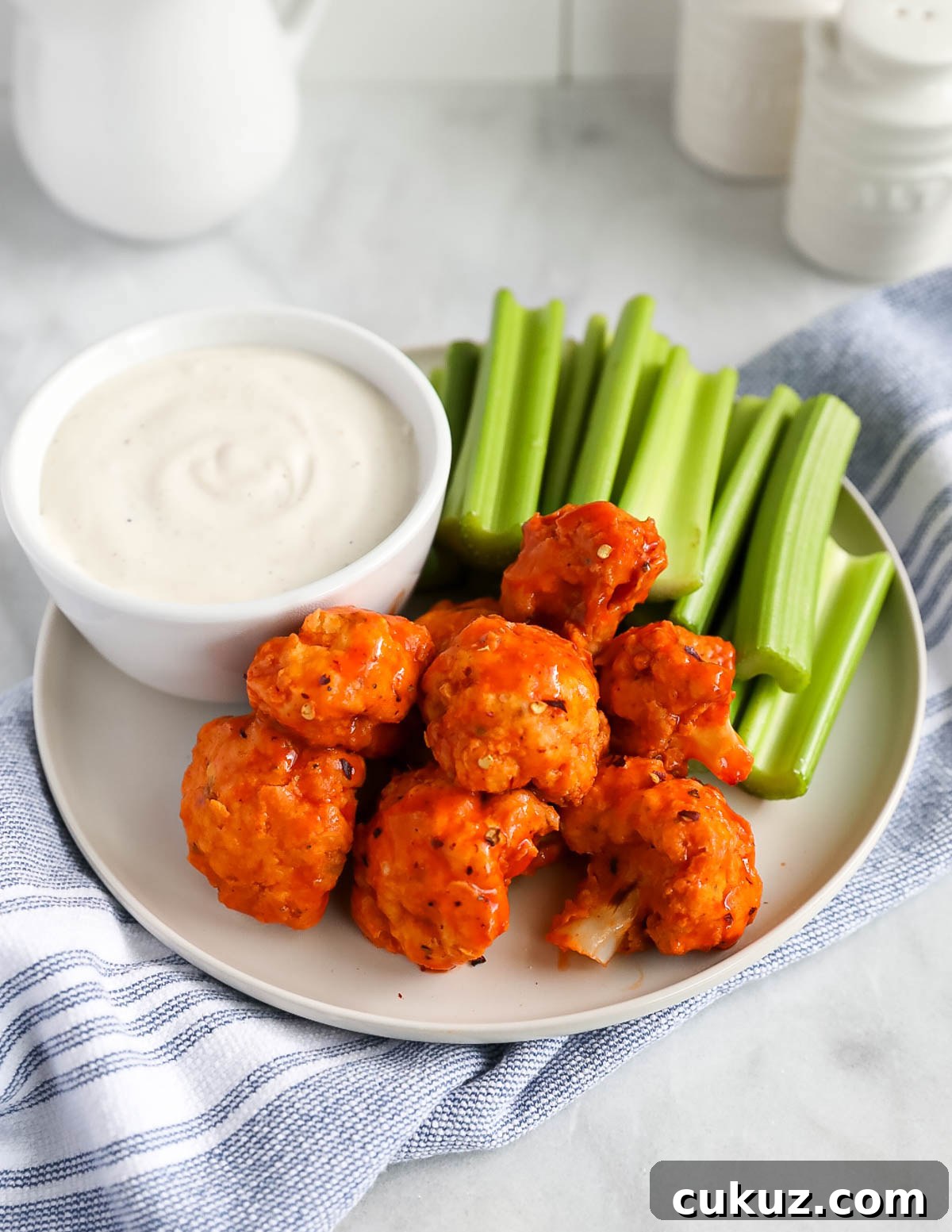 Cauliflower bites on a plate with celery sticks and vegan ranch