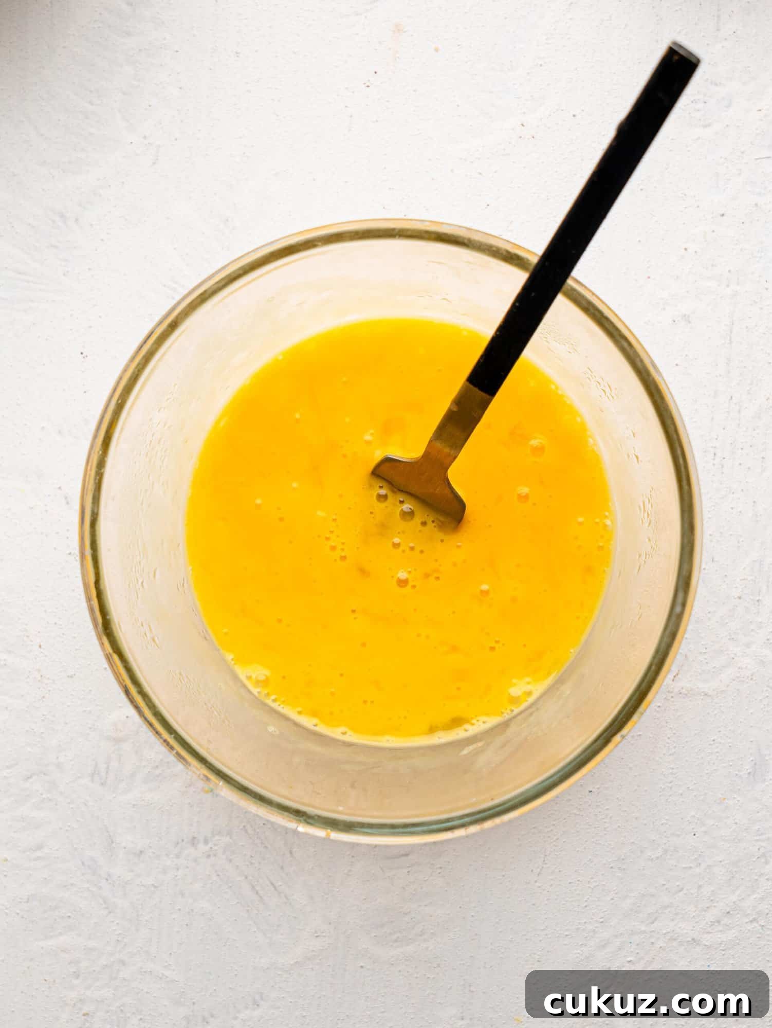 Whisked Eggs in a glass mixing bowl.