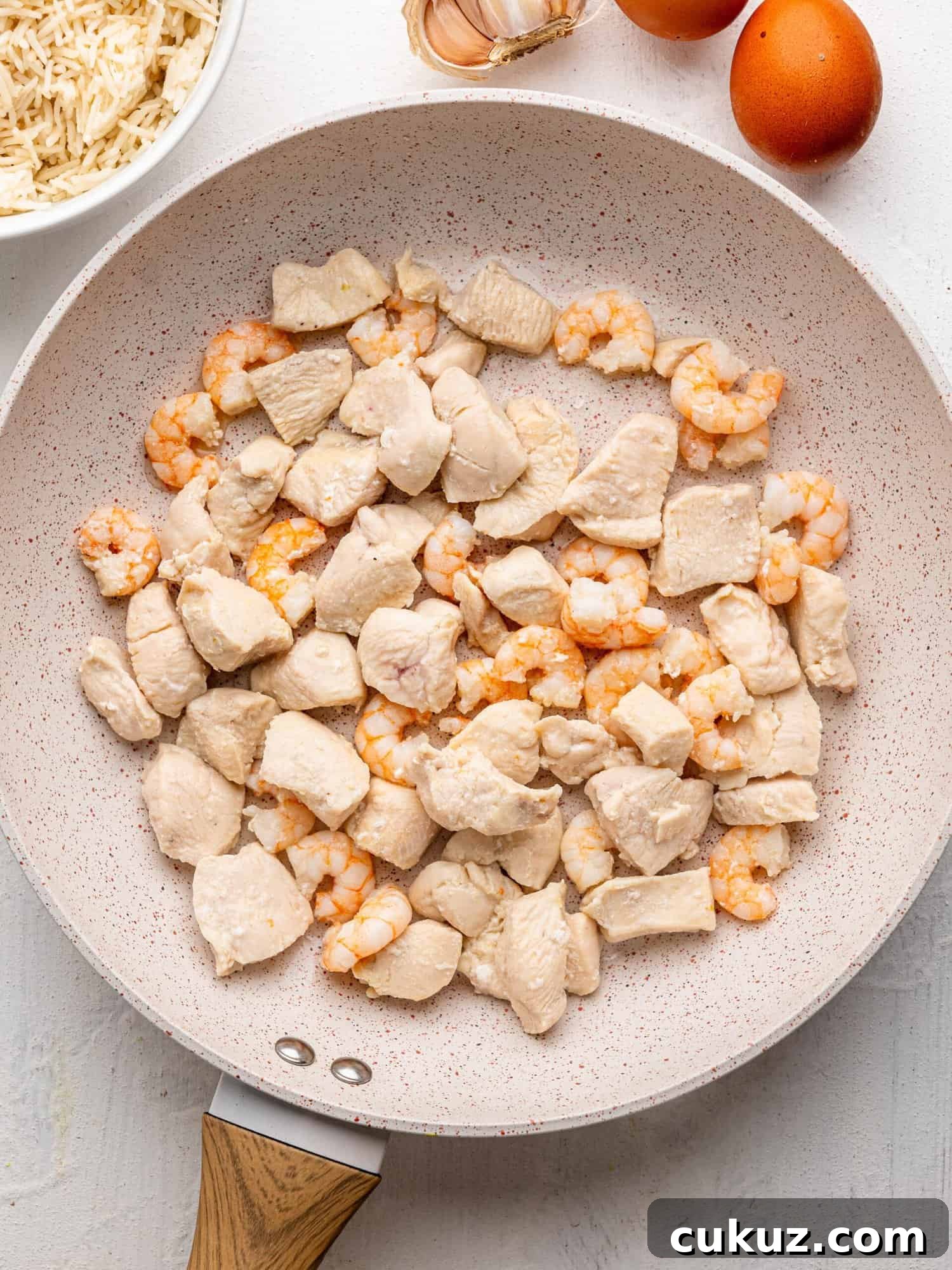Cooked chicken and shrimp in a frying pan.
