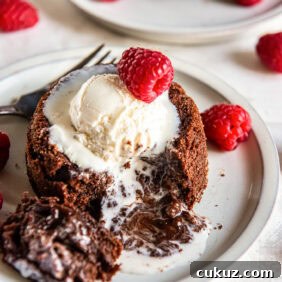 Chocolate lava cake cut into with a gooey molten center flowing onto the plate.