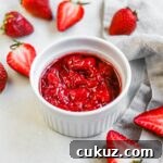 Homemade strawberry compote (for ice cream, yogurt, desserts, and more) in a white ceramic ramekin with cut strawberries.
