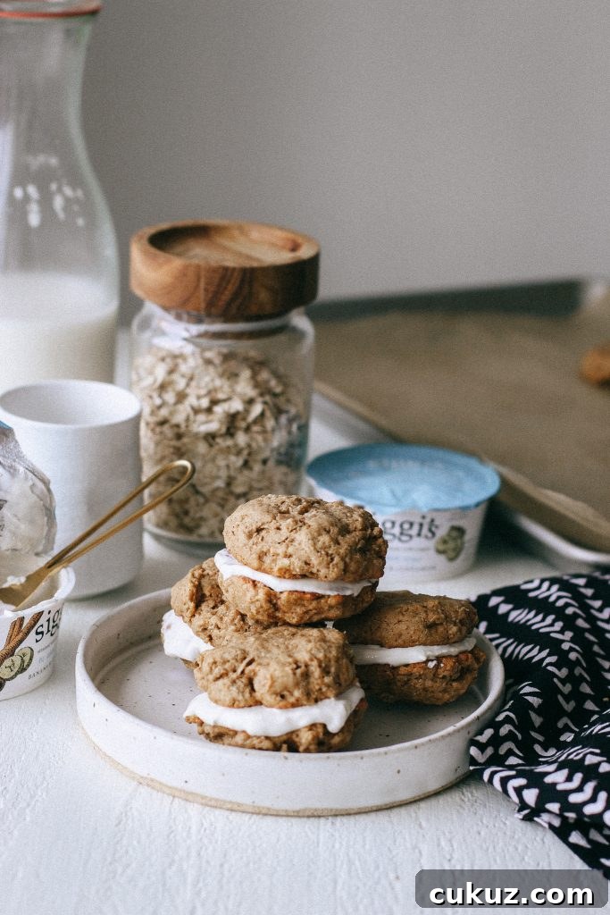 Low-Sugar Gluten-Free Oatmeal Cookie Sandwich with Cinnamon Yogurt Filling 2 Oatmeal cookie sandwiches with yogurt filling on a white plate