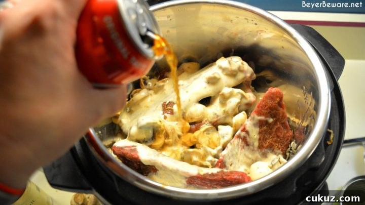 Creamy cola sauce bubbling around cubed steaks in the Instant Pot.