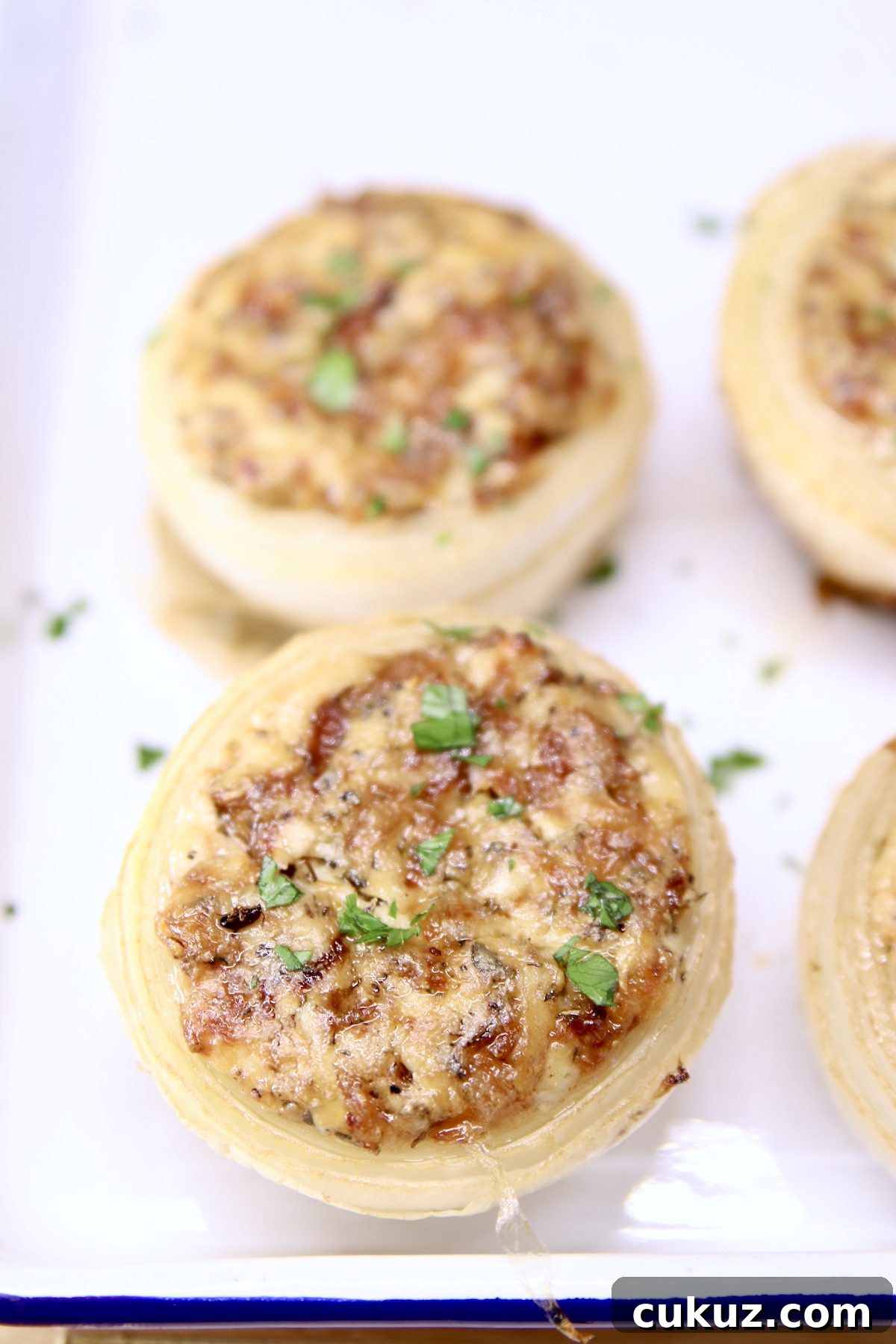 Stuffed Onions are a flavorful and delicious side dish for any meal on the grill. Caramelized onions mixed with cheese, herbs and spices stuffed inside onion shells are grilled alongside steaks, chicken or pork for an easy addition to any meal. Stuffed onions on a white tray