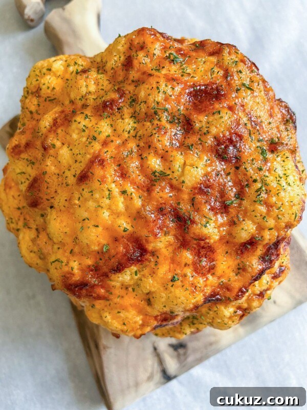 Viral Cabbage Boil Recipe: How to Make the Trendy Cabbage Pot 5 A Whole Roasted Cauliflower head with a golden-brown crust, sprinkled with herbs, rests elegantly on a wooden cutting board.