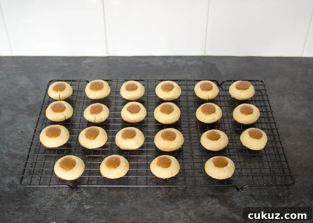 Thumbprint cookies filled with caramel on a wire rack