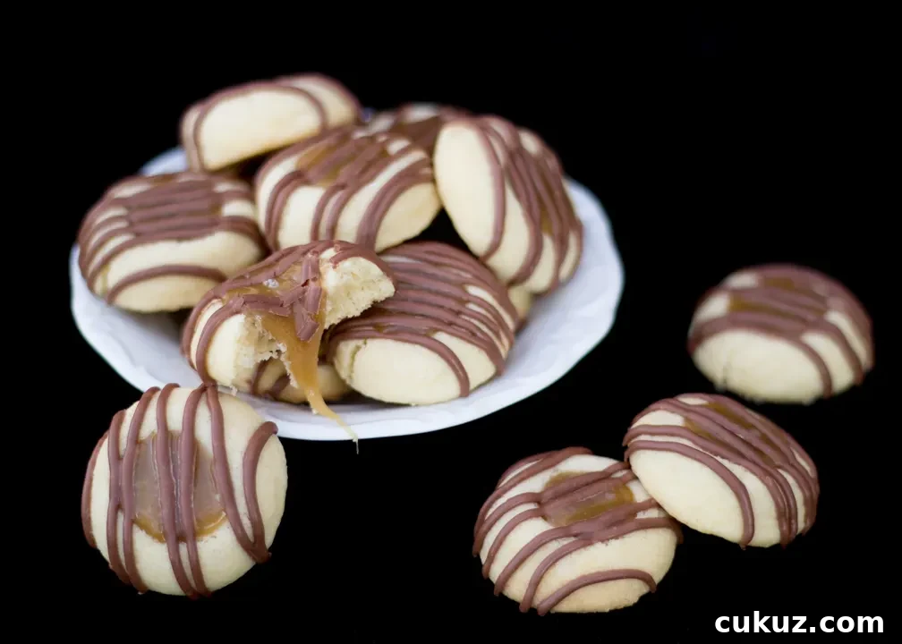 Twix thumbprint cookies in a white plate with caramel oozing out