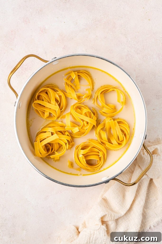 Creamy Dairy-Free Salmon Tagliatelle Recipe 6 Adding the tagliatelle into the oat milk and stock in the pot.