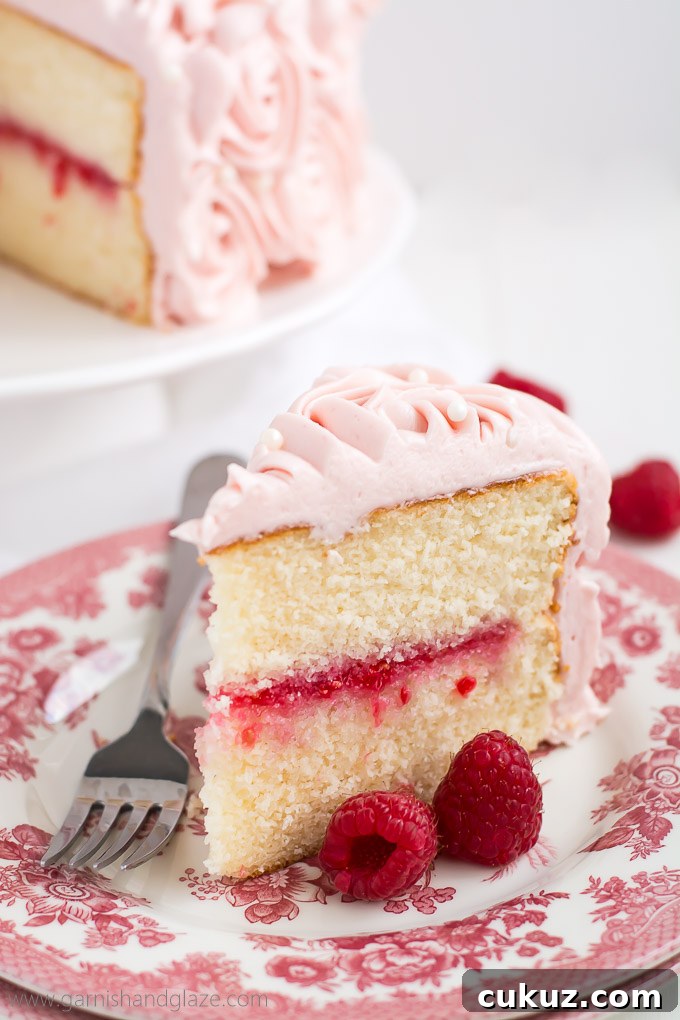 Raspberry Rose Cake is made up of two tender white cakes with sweet raspberry jam sandwiched between and then covered in rose-like swirls of silky smooth raspberry cream cheese frosting.