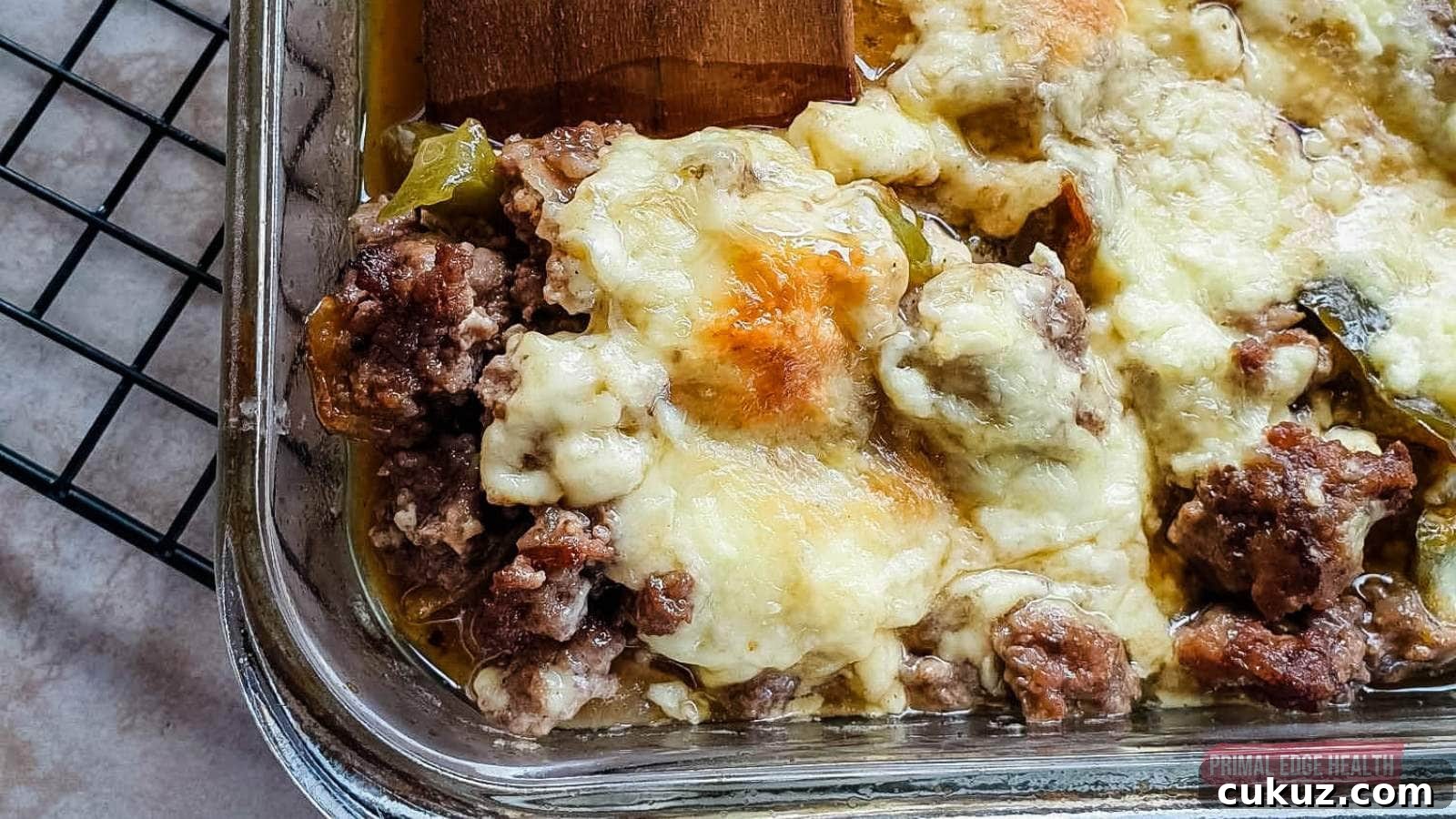 Image shows a wooden spatula cutting philly cheesesteak casserole from baking dish.