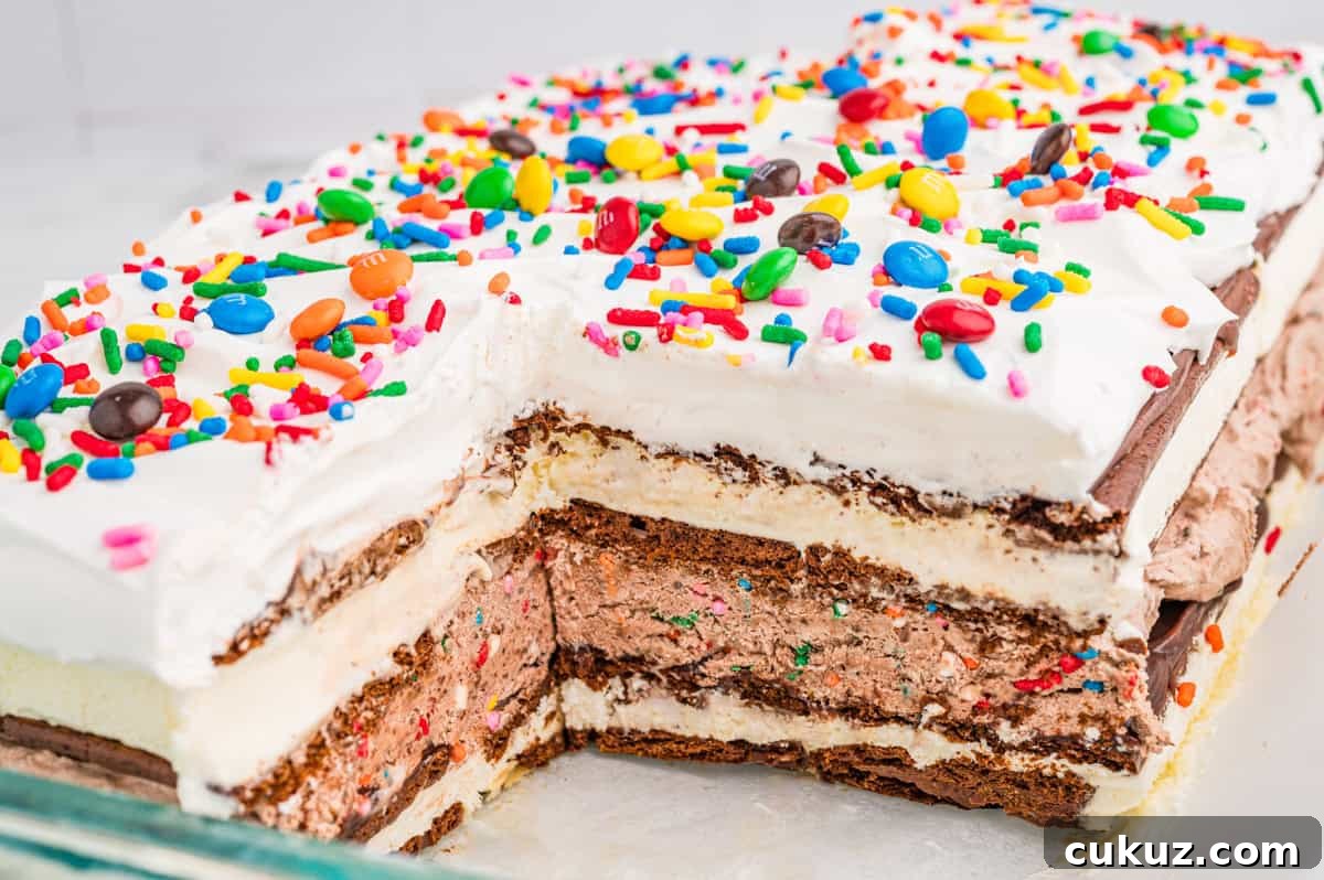 A layered ice cream sandwich cake topped with cool whip and rainbow sprinkles.