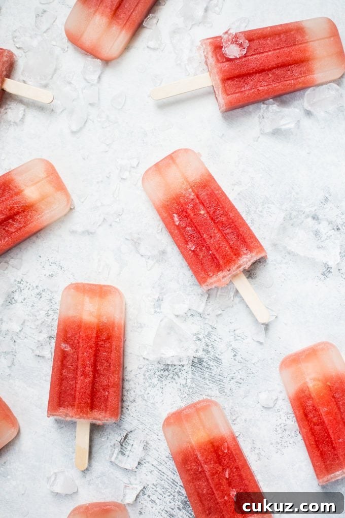 watermelon margarita popsicles on a counter with ice cubes