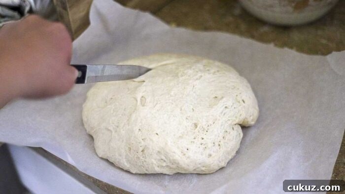How to Make Delicious Bread with Sourdough Discard 11 slicing sourdough discard bread dough with a knife on parchment paper