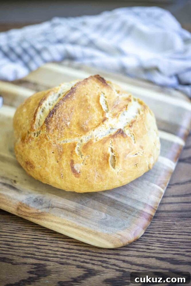 How to Make Delicious Bread with Sourdough Discard 4 loaf of crusty sourdough discard bread on a wood cutting board sitting on a wood table with a plaid towel in the background