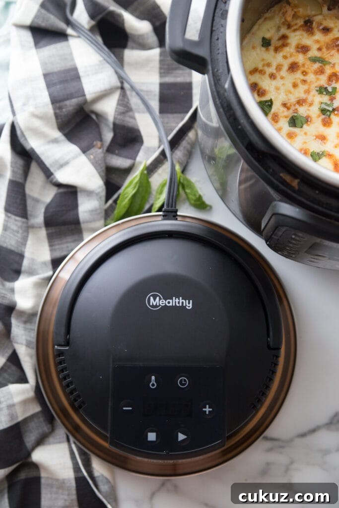 Overhead shot of Mealthy CrispLid on white marble countertop and black and white checkered tablecloth. In the corner you can see a partial view of a finished Instant Pot Zucchini Lasagna with nice crispy cheese topping.