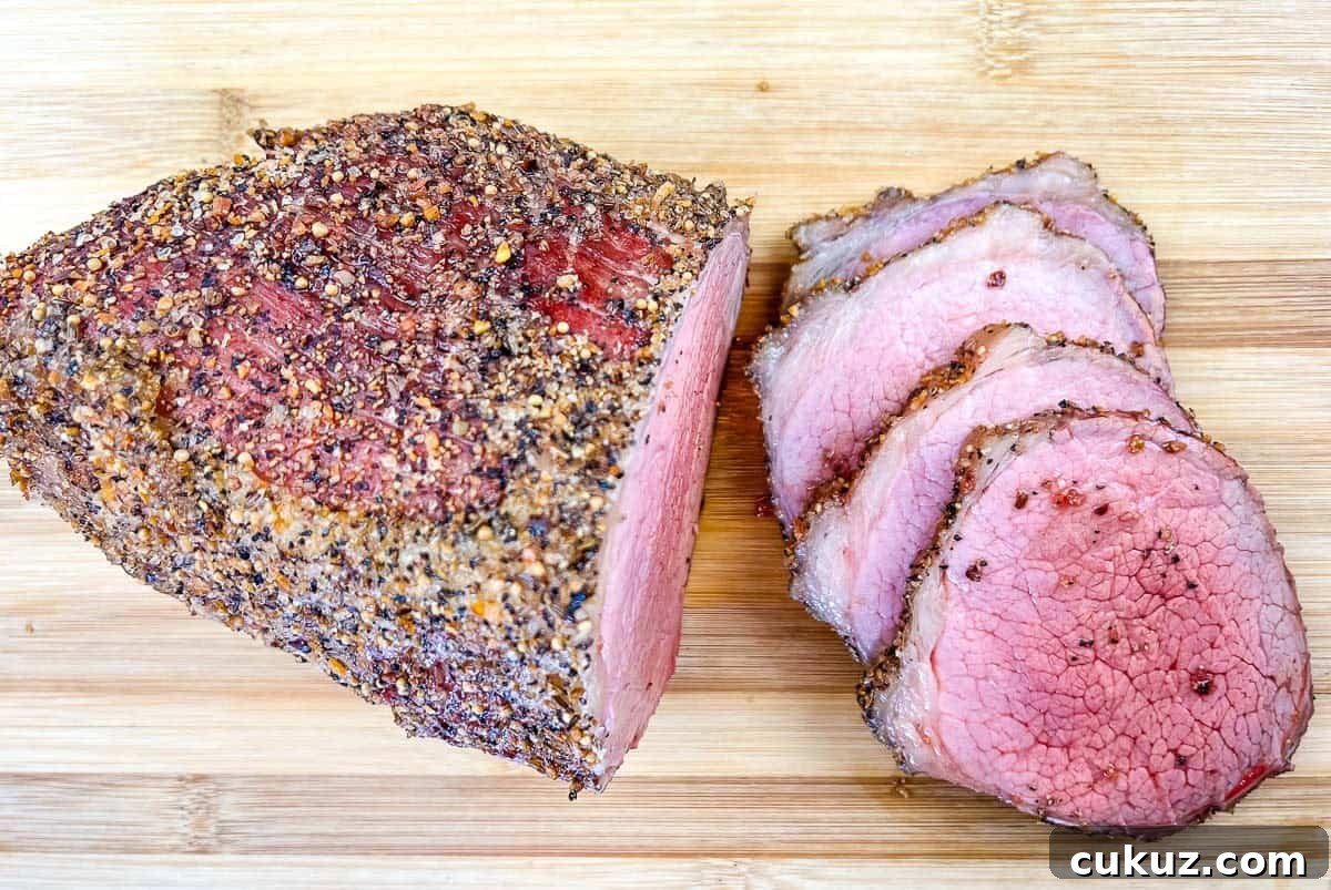 A whole and sliced smoked eye of round with on a wooden cutting board.