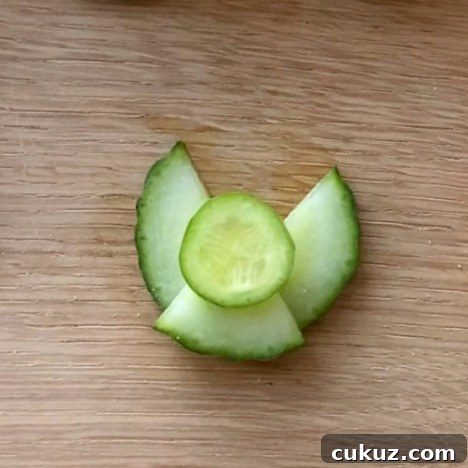 Cucumber slices arranged as an angel on a wooden surface.
