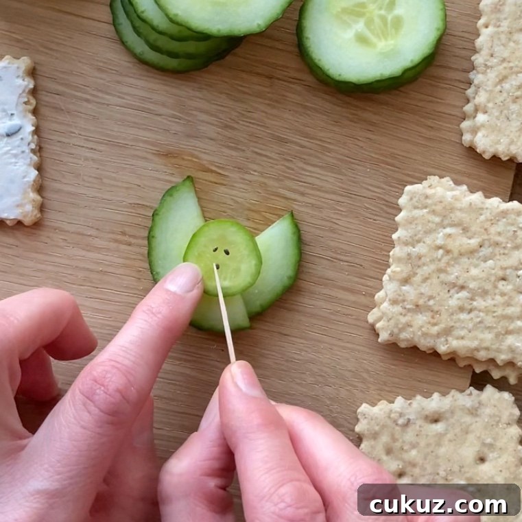 A person uses a toothpick to place seeds on a cucumber slice.