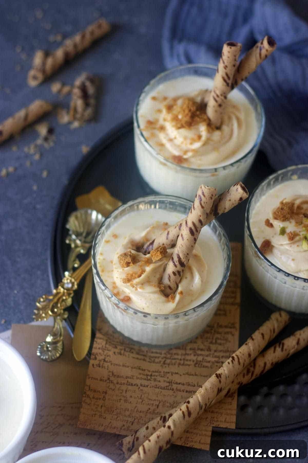 3 ramekins filled with bhapa doi sweet and garnished with wafer biscuits on top