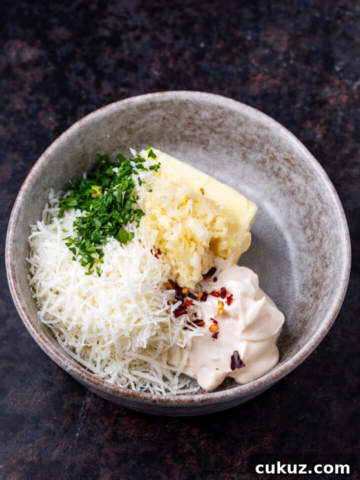 gray bowl with butter, mayo, parsley, parmesan cheese and grated garlic