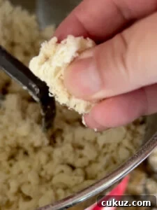 Hand pinching a piece of dough to see if it's ready.