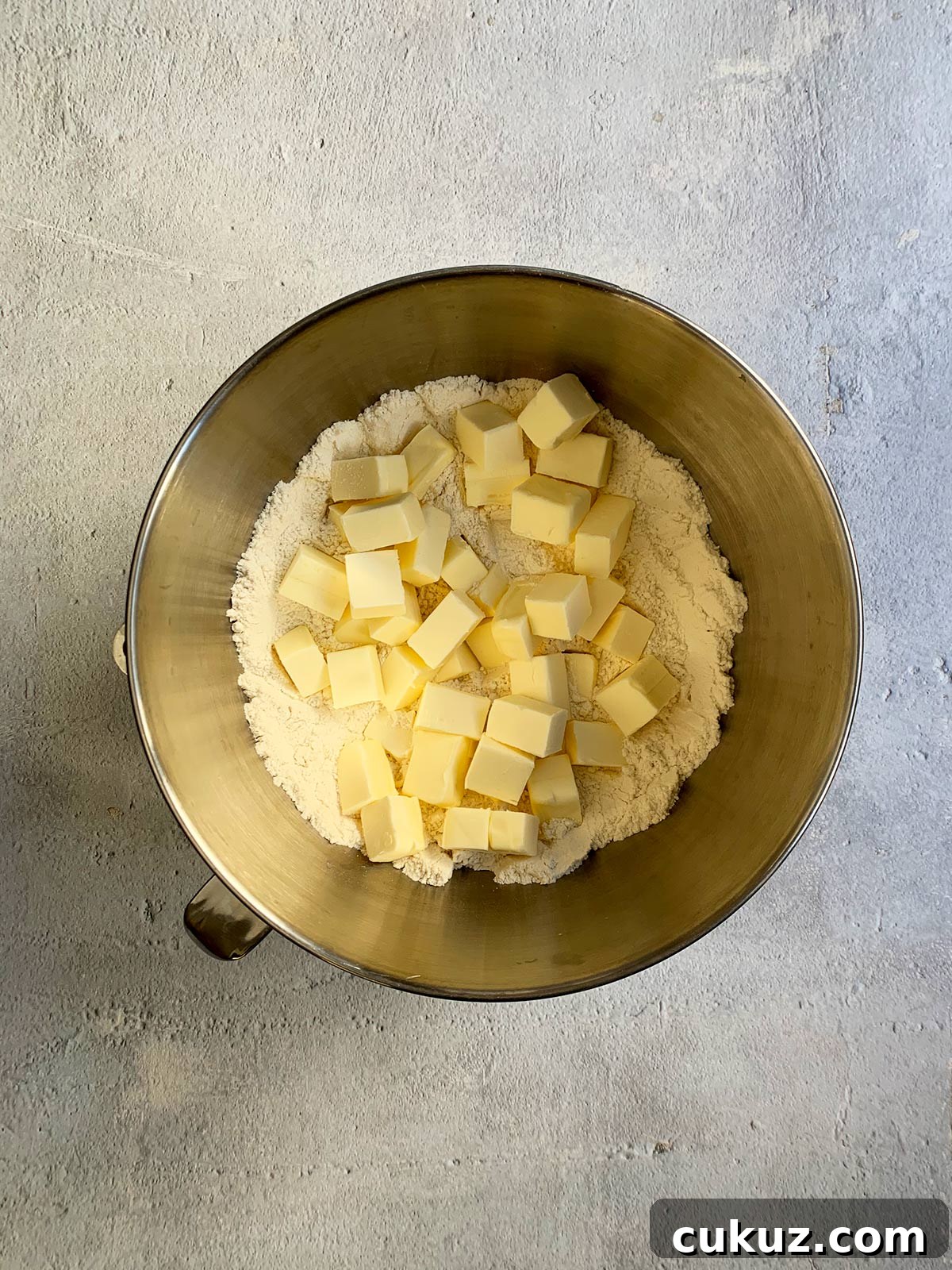 Cubes of butter over flour mixture in mixer bowl.