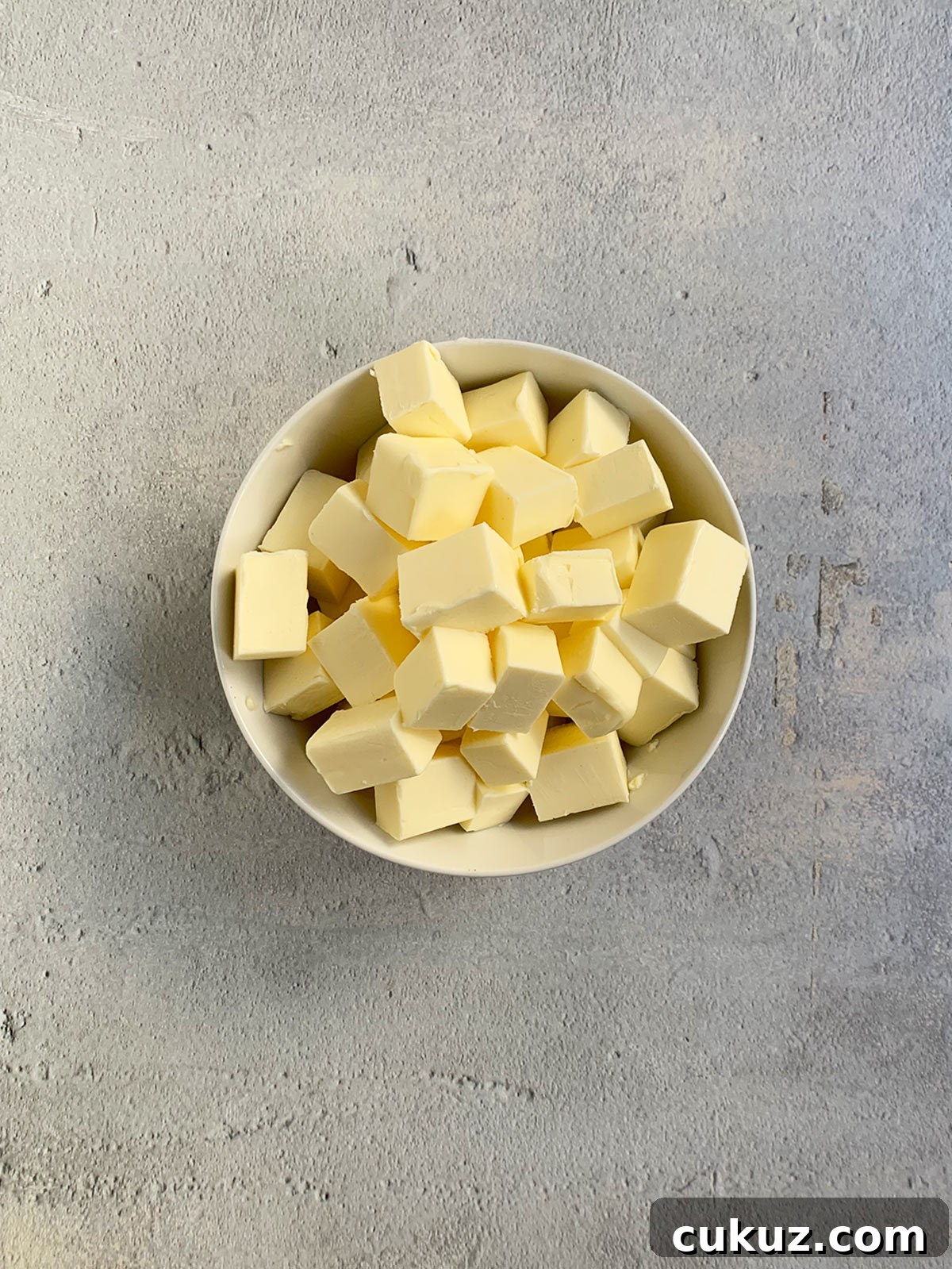 Butter cut into cubes in a white bowl.